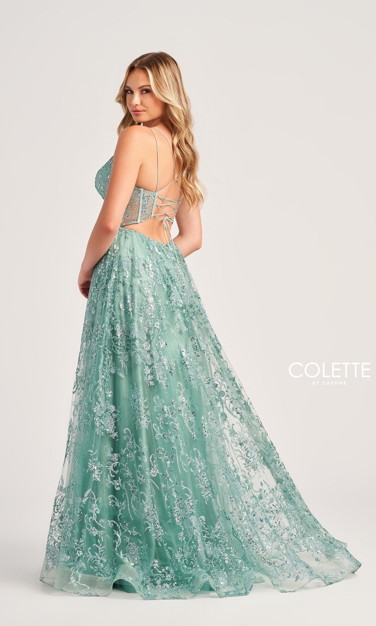 Woman wearing the Glitter-Tulle Colette Long Prom Dress CL5134, a light green, floor-length gown with lace detailing, thin straps, and a corset-style bodice, standing against a plain background.